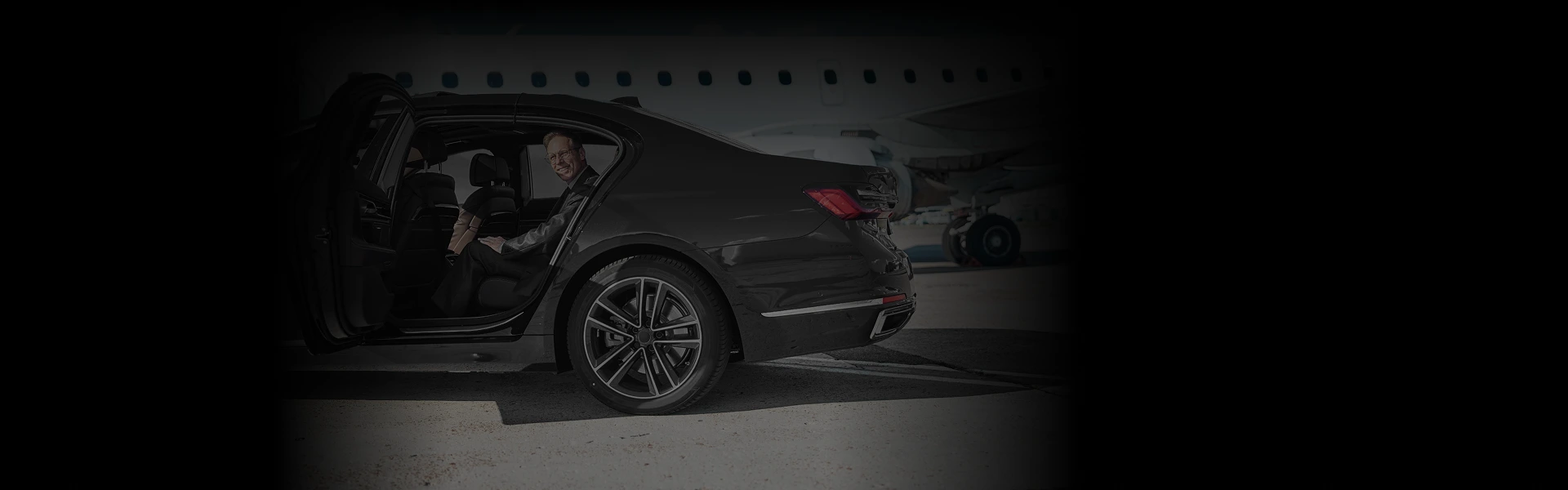 Business traveler boarding a black luxury sedan at Midway Airport