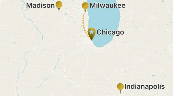 A regional map of the Midwestern United States showing a route between Milwaukee and Chicago (marked with a star pin) along the coast of Lake Michigan, indicated by a dotted line. Madison and Indianapolis are also marked as points of interest.